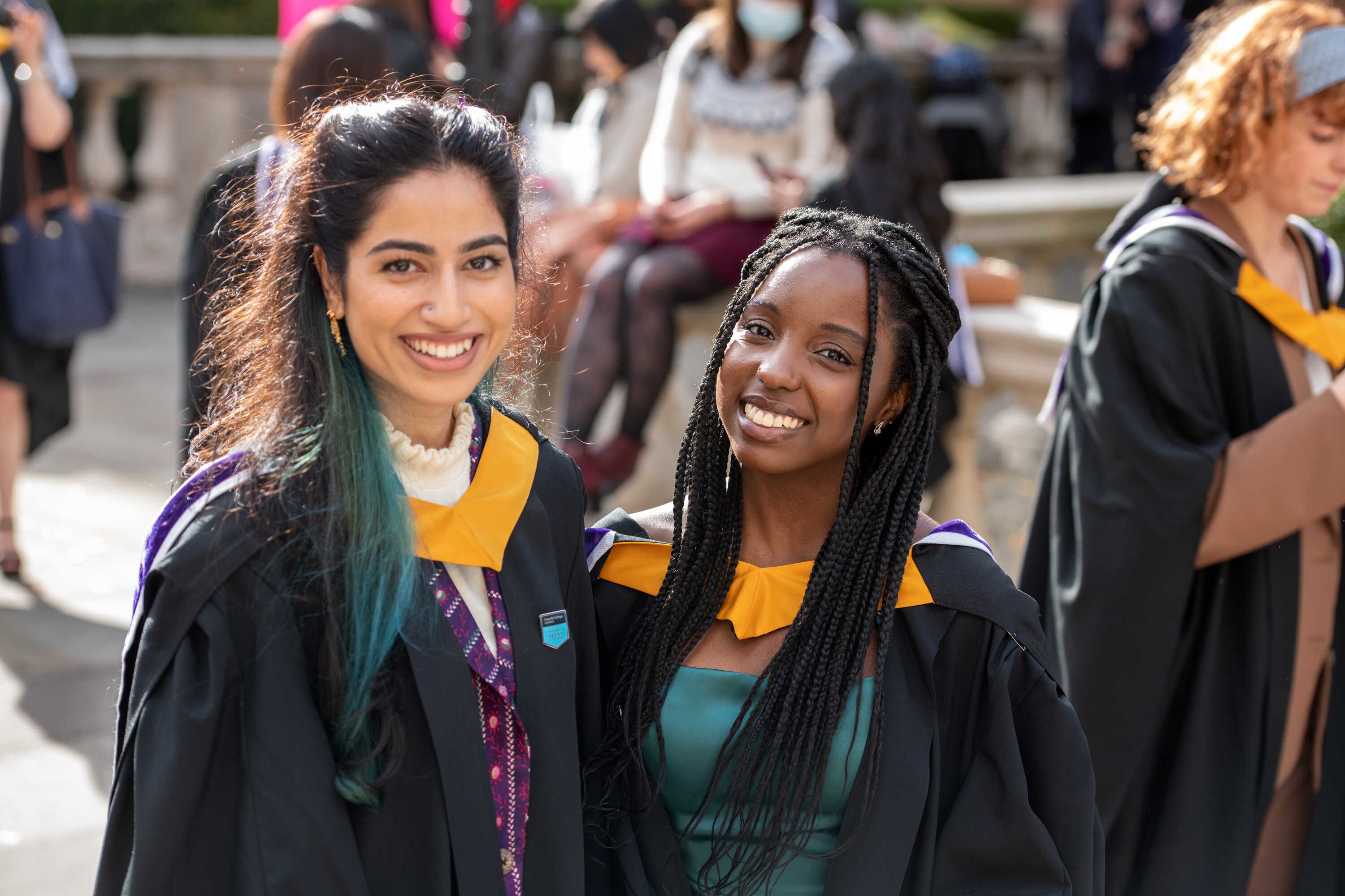 Two students wearing gowns with yellow collars