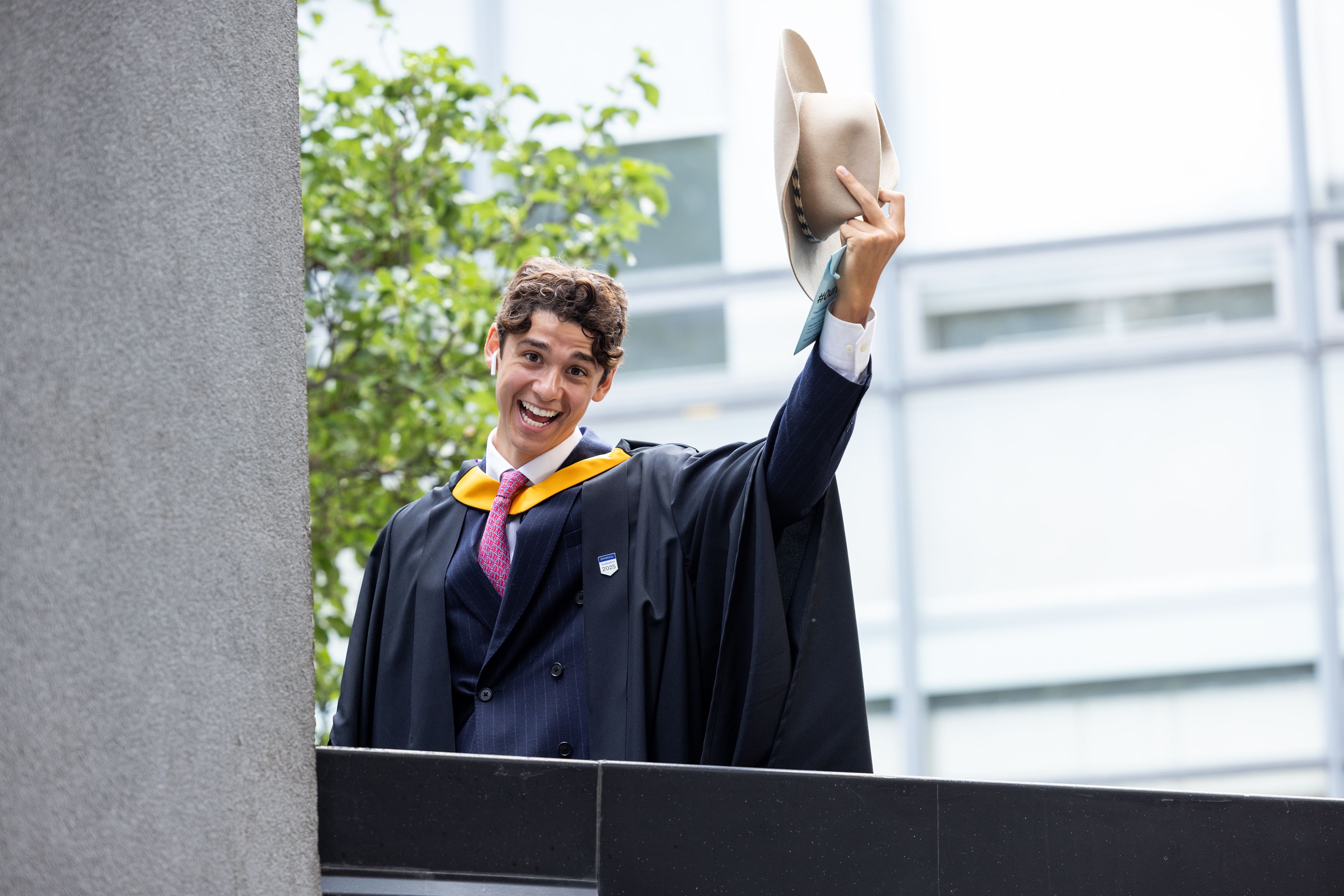 A graduate raises their hat to the camera