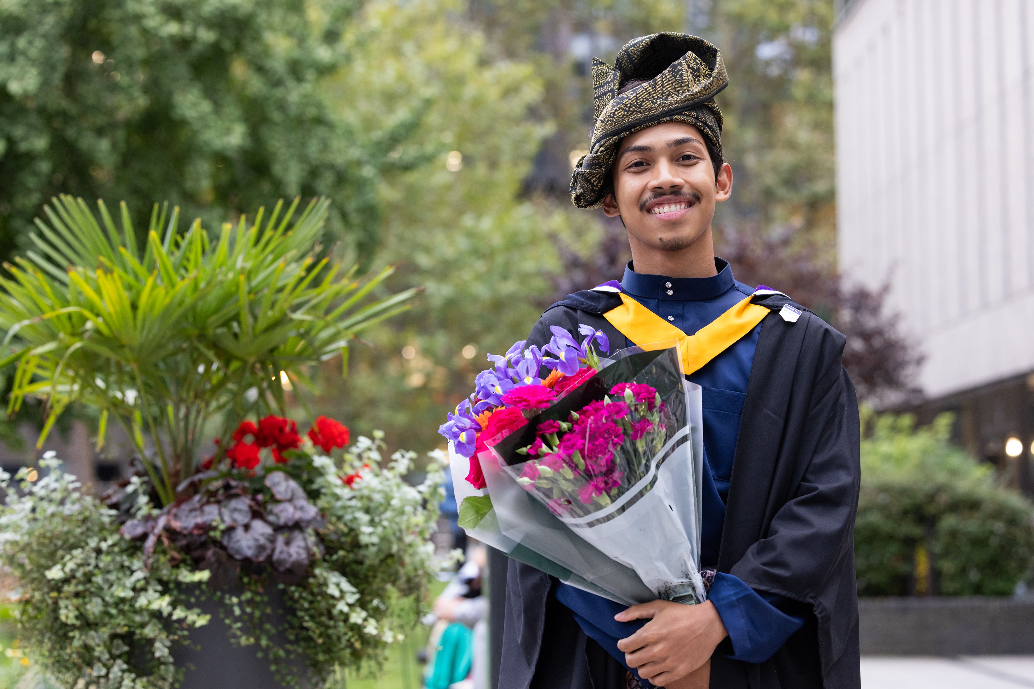 A graduate poses with flowers