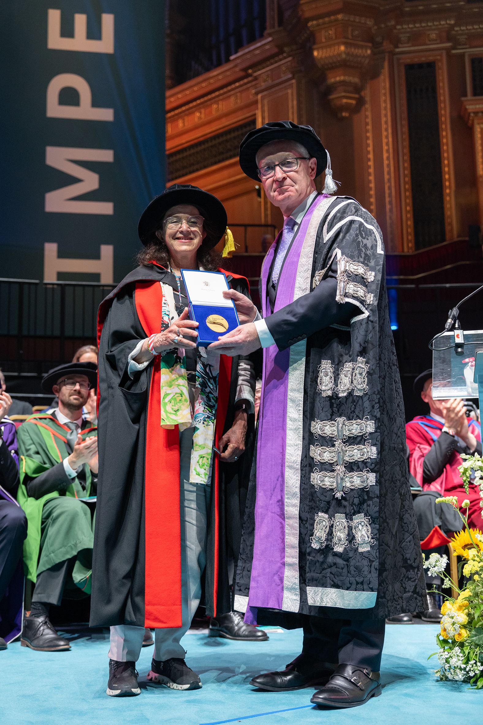 An awardee on stage with President Hugh Brady