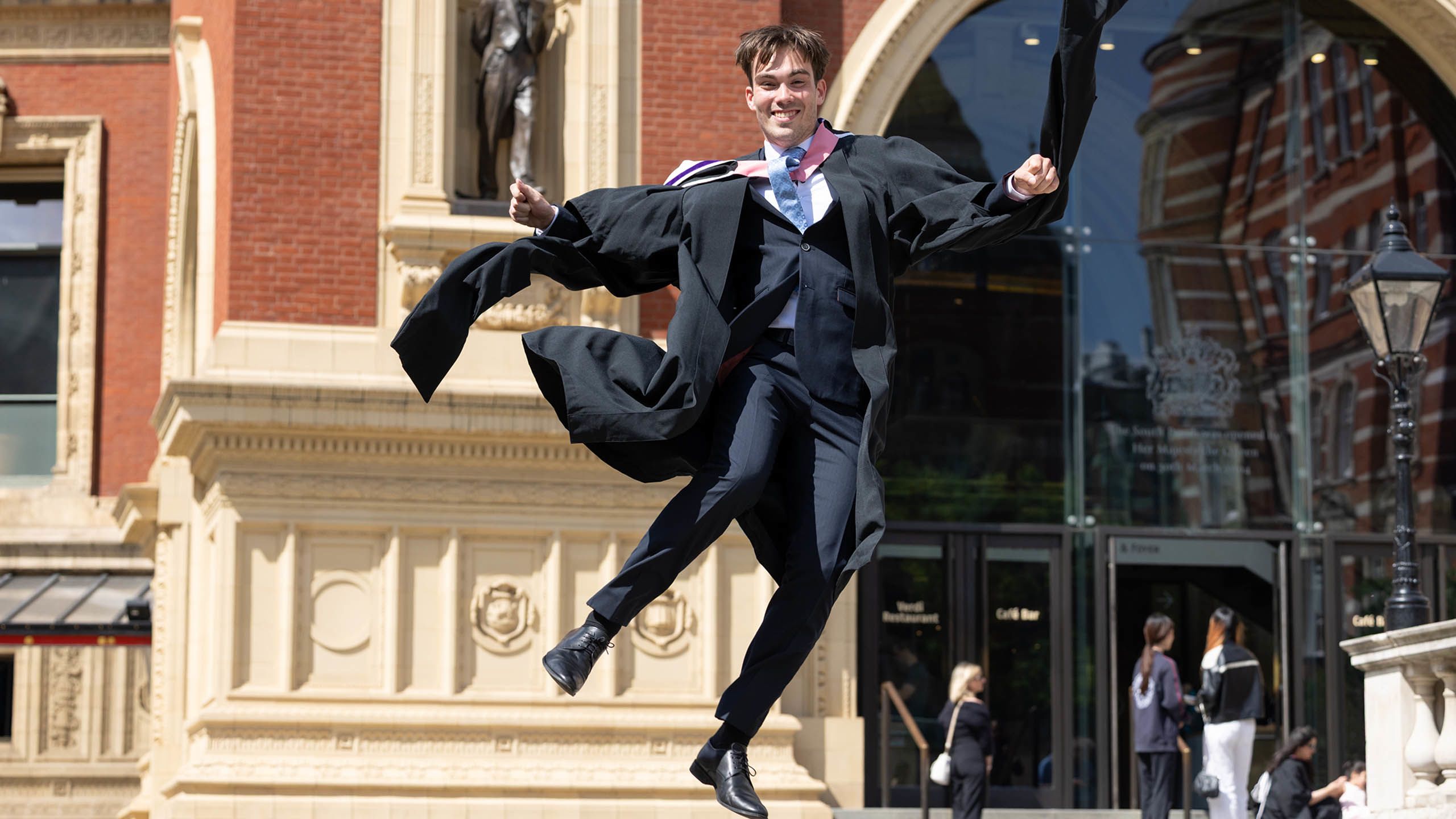 A graduate jumping for joy outside the Royal Albert Hall